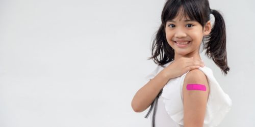 Holčička ukazující ruku po očkování.